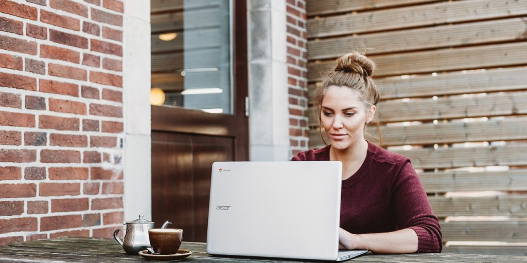 Woman working on laptop drinking coffee